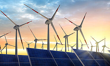 Windkraftanlagen vor einem Sonnenuntergang, die erneuerbare Energien darstellen.