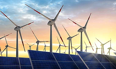 Windkraftanlagen vor einem Sonnenuntergang, die erneuerbare Energien darstellen.