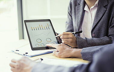 Analyst betrachtet Diagramme auf einem Tablet, um Daten zu bewerten.