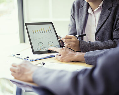 Analyst betrachtet Diagramme auf einem Tablet, um Daten zu bewerten.