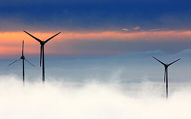 Windkraftanlagen stehen vor einem bewölkten Himmel.