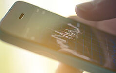 Nahaufnahme von Händen, die ein Smartphone halten.